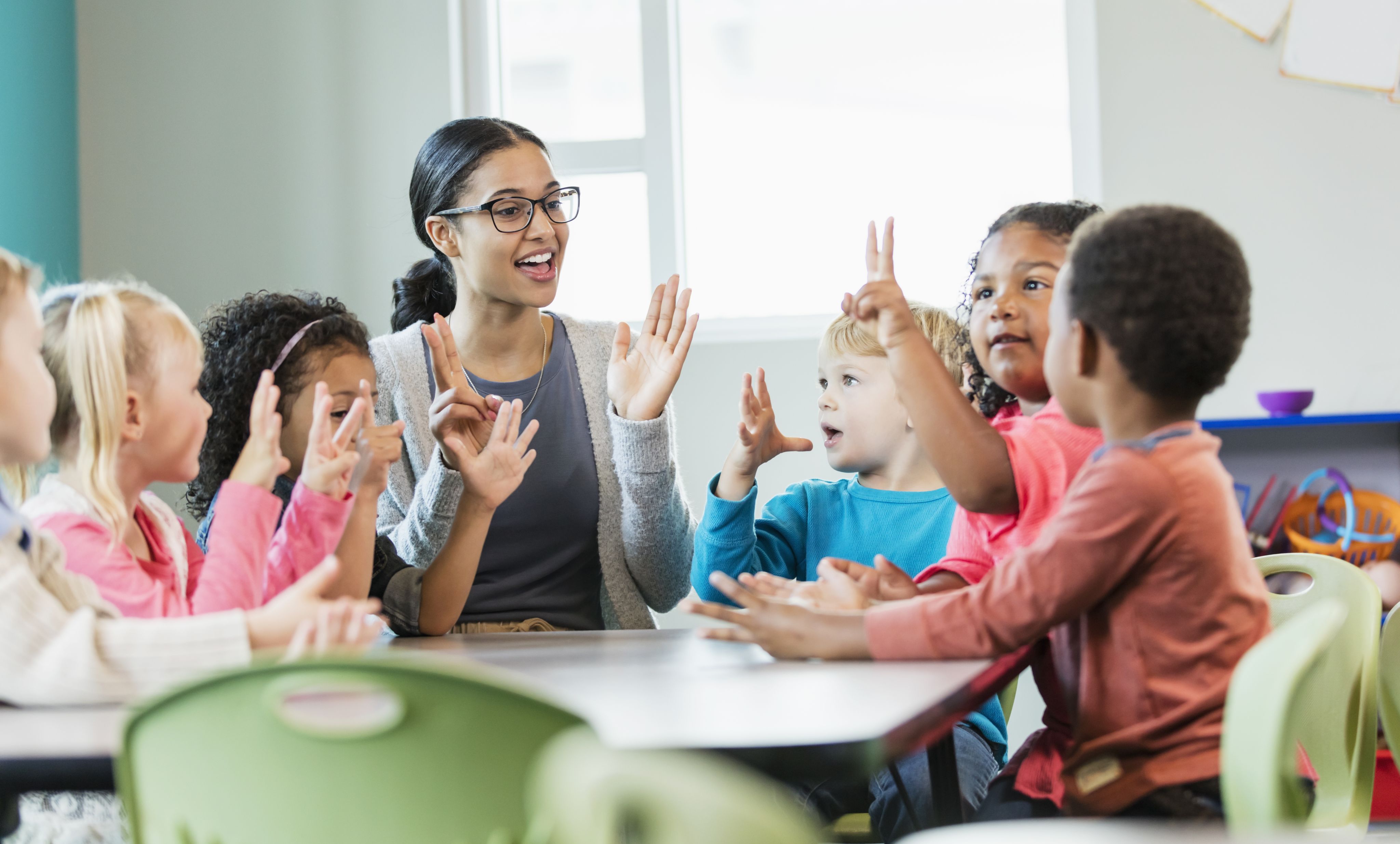 Teacher sitting with a group of children, engaged in a learning game