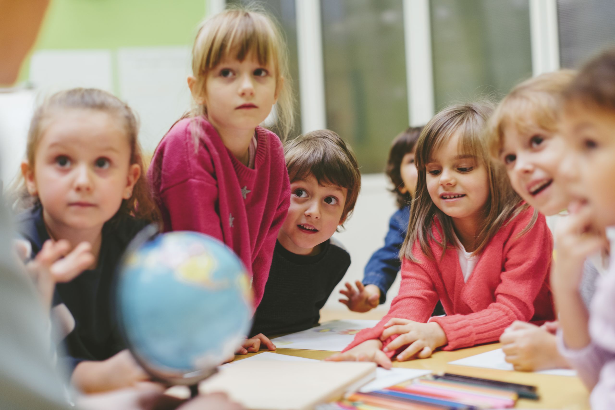 Image of youg children listening intently to their teacher.
